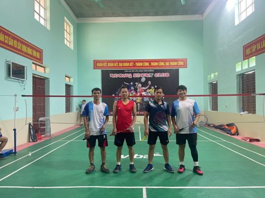 A group of men standing in a badminton courtDescription automatically generated